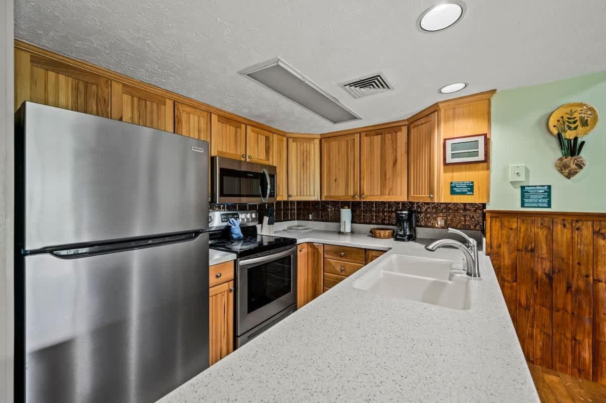 The full kitchen with stainless appliances and pale stone counters · © Above The Clouds