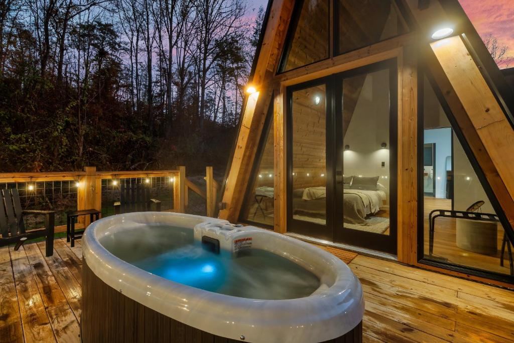 The private hot tub on the deck, lit at dusk · © An Escape to the Forest