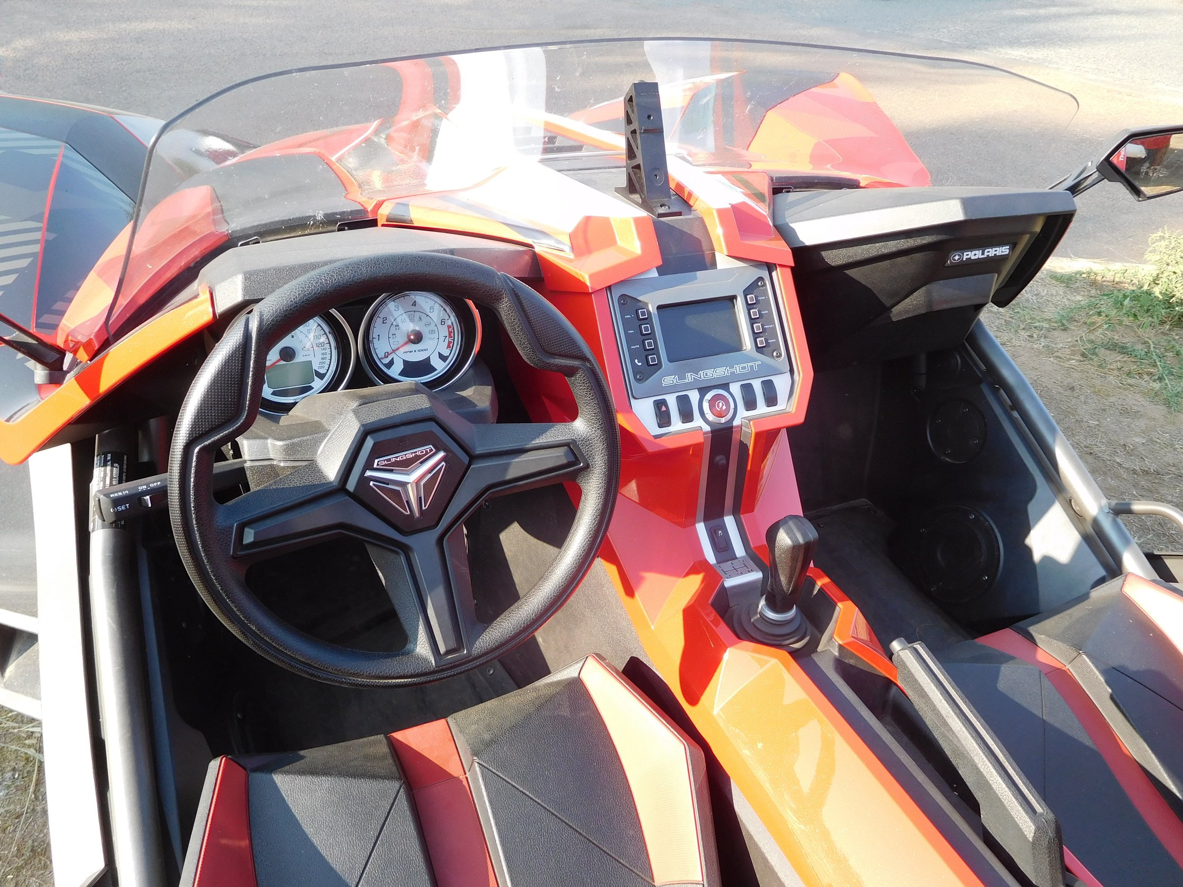 Inside a Slingshot: a car-style wheel, a gear lever and bucket seats, no roof