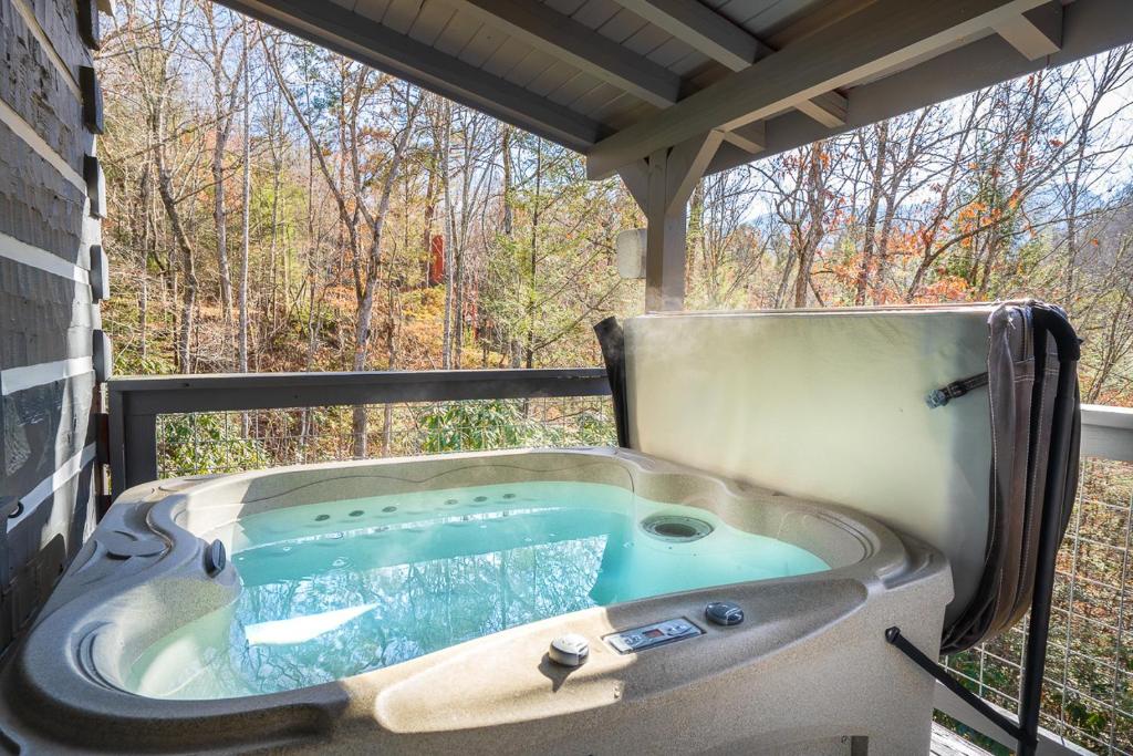 The hot tub under the porch roof, facing the woods · © Bear Necessity