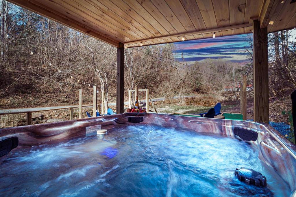 The private hot tub on the covered deck, facing the creek and trees · © Bear Paradise Cabin