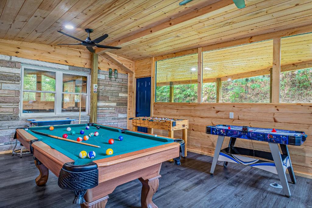 The game room with a pool table, foosball and wide forest windows · © Bear Paradise Cabin