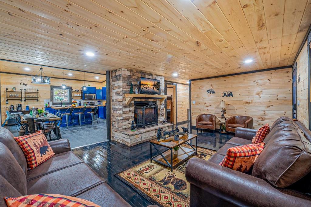 The great room around a stone fireplace and deep leather seating · © Bear Paradise Cabin