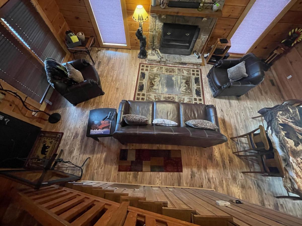 The log-walled living room with leather seating and a stone fireplace · © Bears Among Us