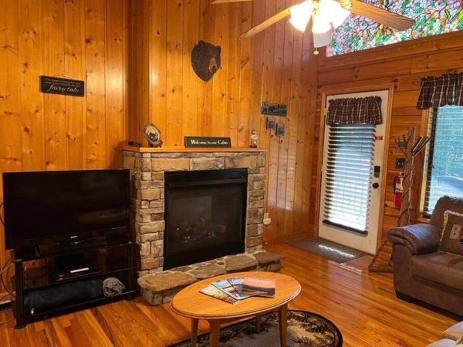 The living room's stone fireplace under a stained-glass window · © Beary Tale
