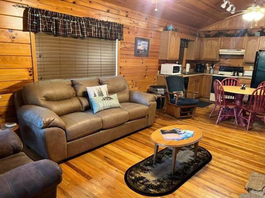 The open living and kitchen area with a leather sofa and dining set · © Beary Tale