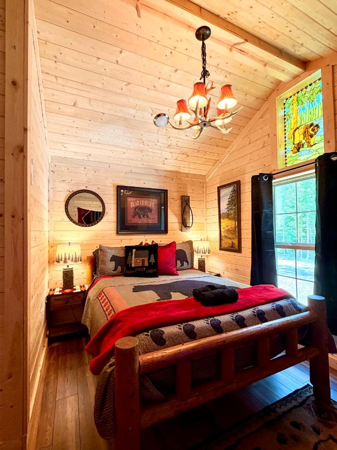 The bedroom under a bear-themed quilt, lit by an antler chandelier · © Big Bear Log Cabin