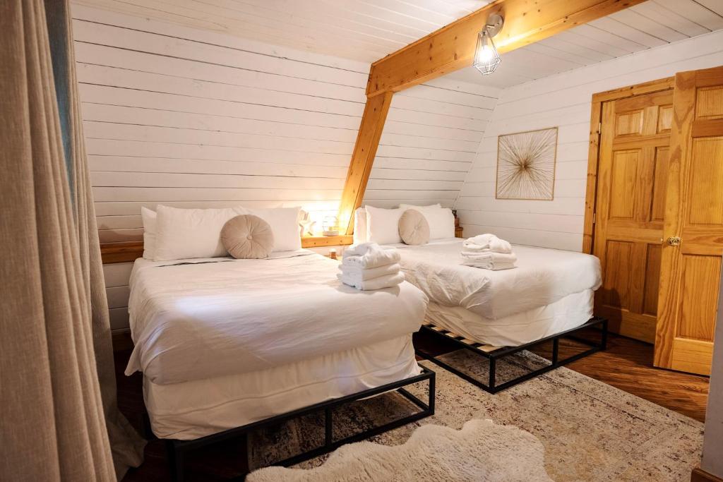 A bedroom with two beds under the sloped ceiling · © Little Green Cabin