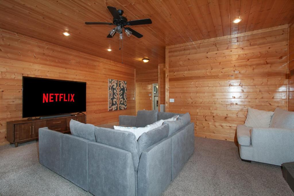 The lower-level media lounge with a wall-mounted TV and sectional · © Bigfoot's Hideout