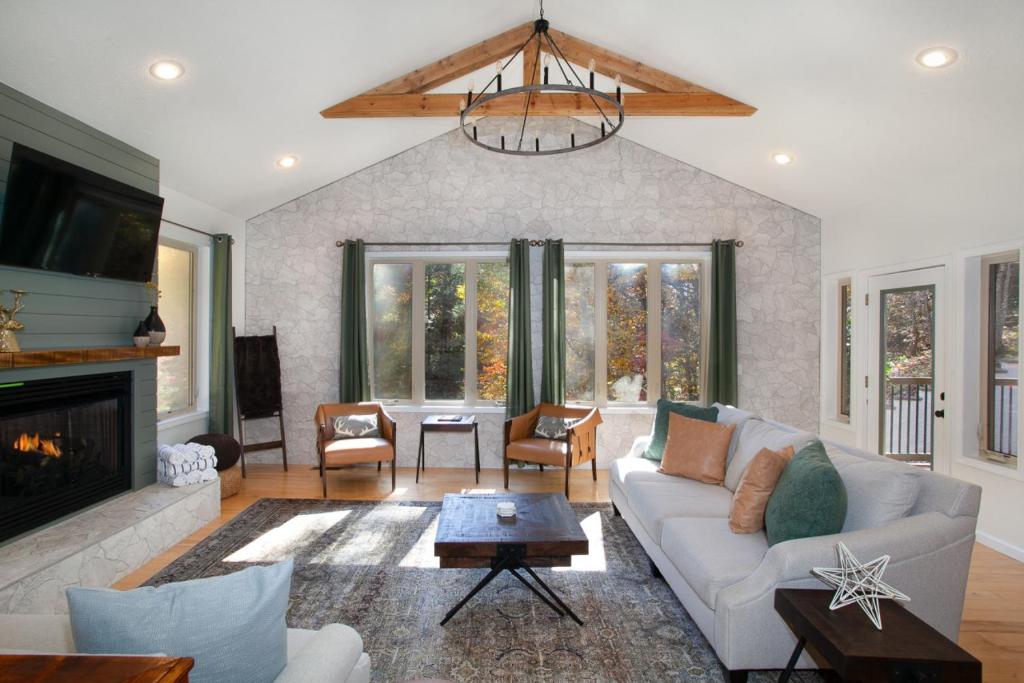 The vaulted great room with a stone fireplace and wall of windows · © Bigfoot's Hideout