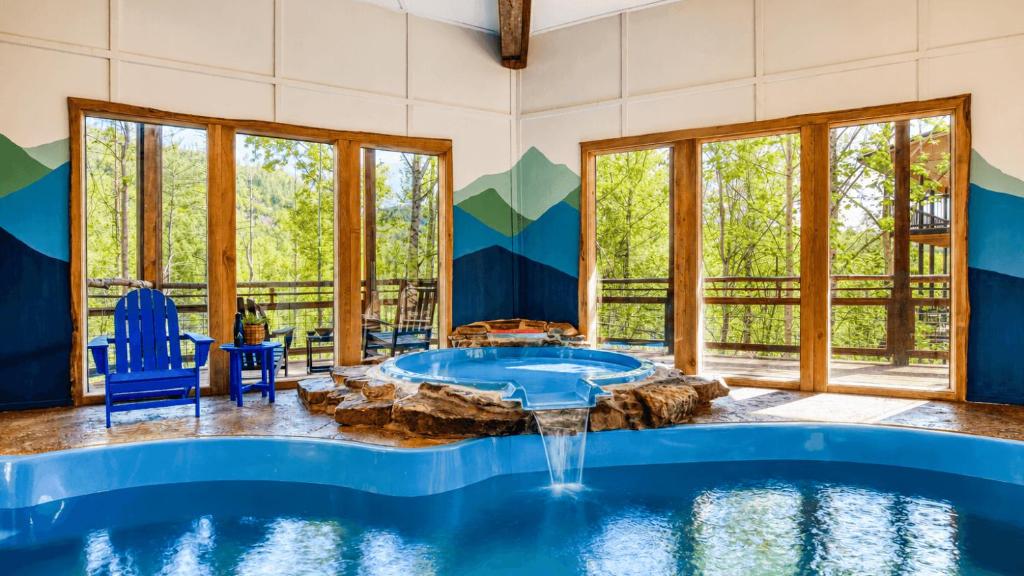 The indoor pool, with the stone-edged hot tub spilling into it · © Birch Lodge