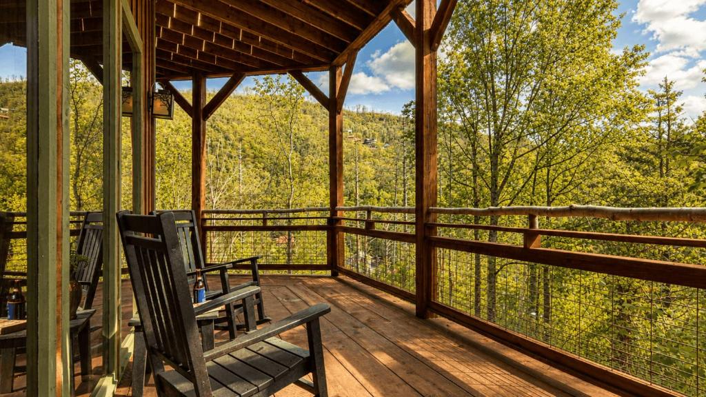 Rocking chairs on a covered deck above the forested slopes · © Birch Lodge