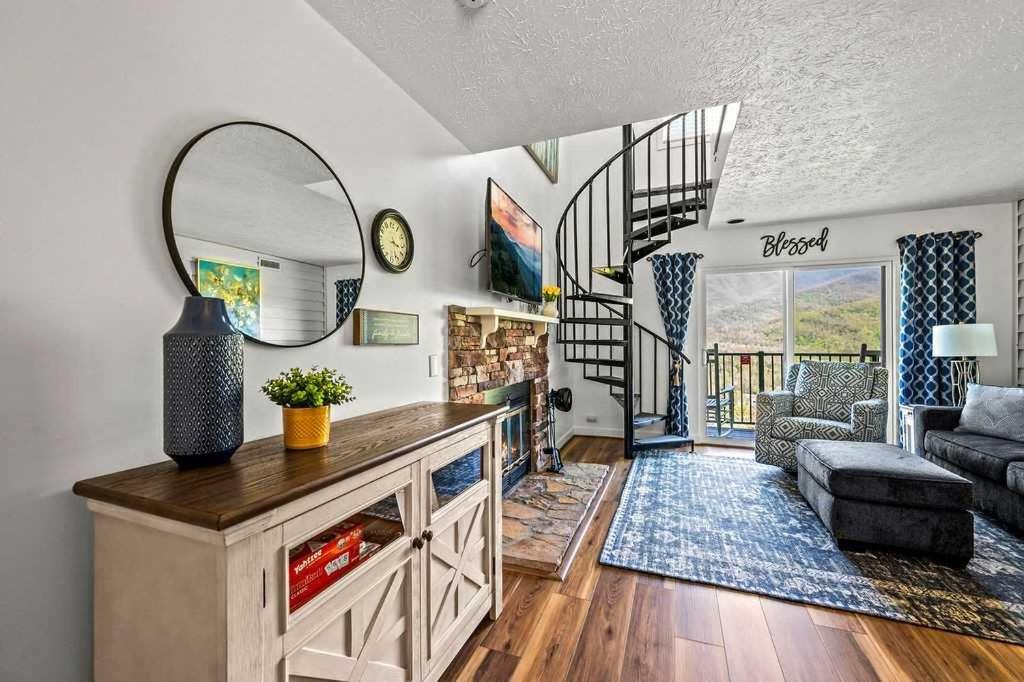 A round mirror, stacked-stone hearth and the black spiral staircase to the loft · © Blessed in the Smokies