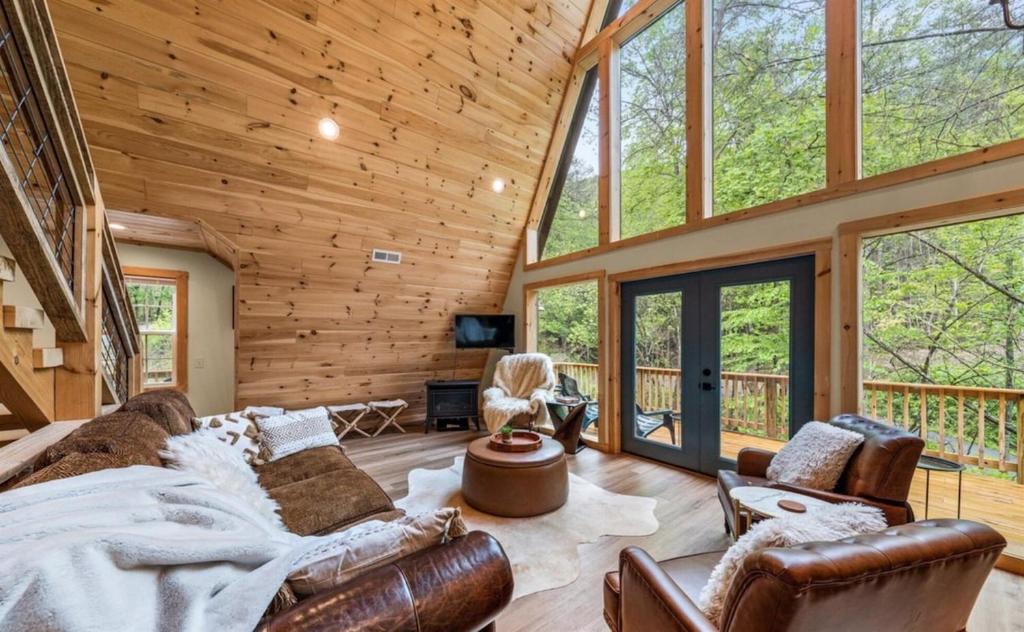 Leather seating under the glass gable, French doors onto the deck · © Cabin Coco