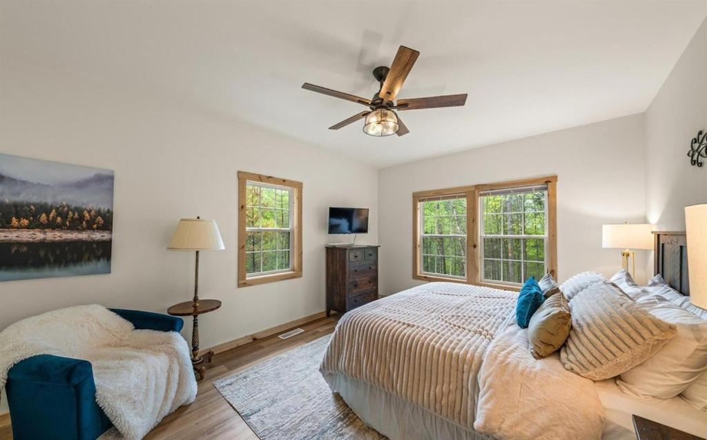 A bedroom with a ceiling fan and windows onto the woods · © Cabin Coco