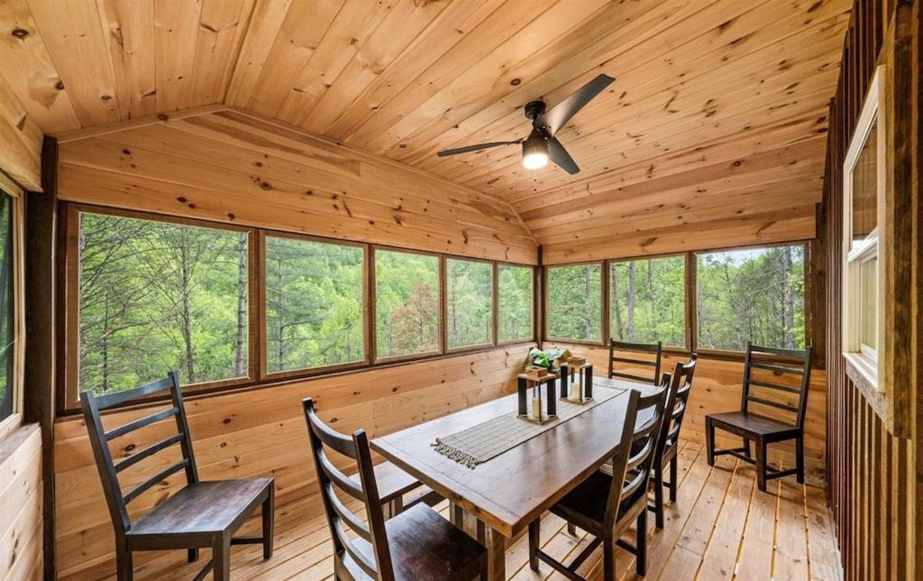The screened dining porch, windows open to the woods · © Cabin Coco