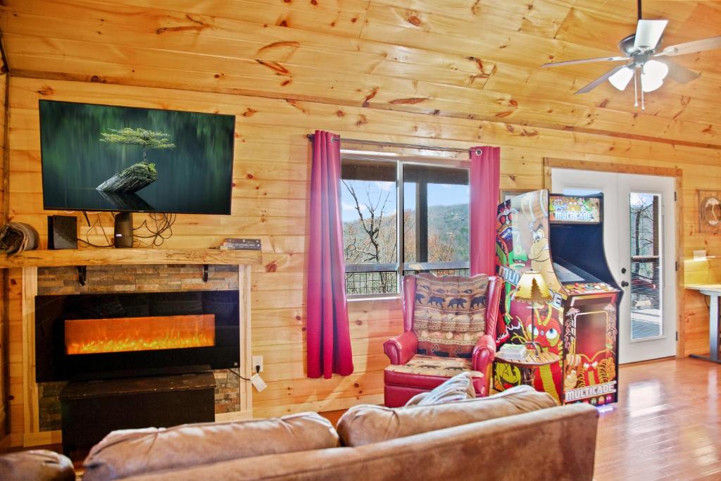 The living room, with electric fireplace, arcade cabinet and a view through the glass · © Cabin In The Smokeys