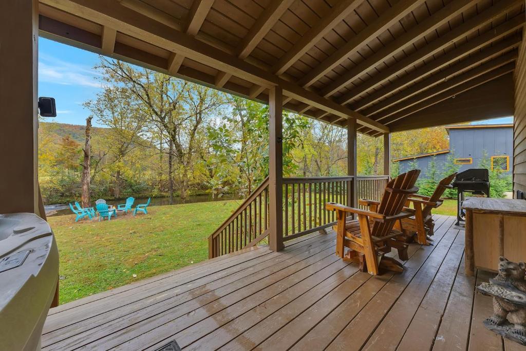 Adirondack chairs on the back porch, the fire pit by the creek · © Creekside Cabin