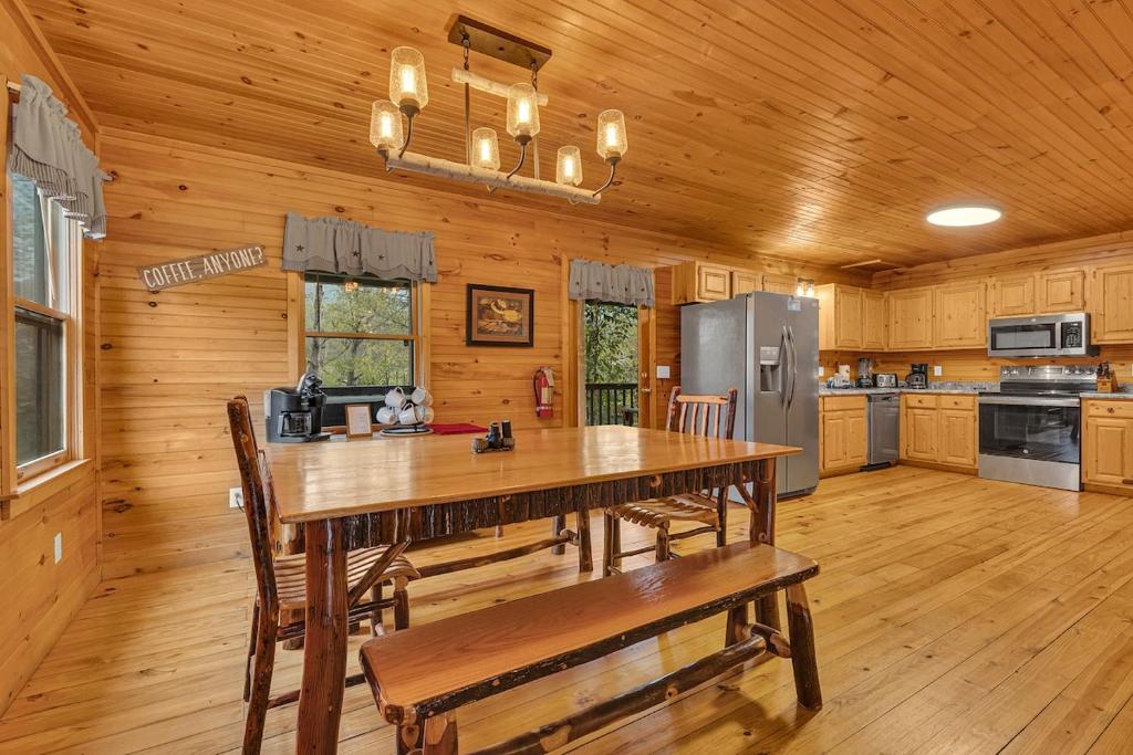 The long rustic dining table in the open pine kitchen · © Creekside Cabin