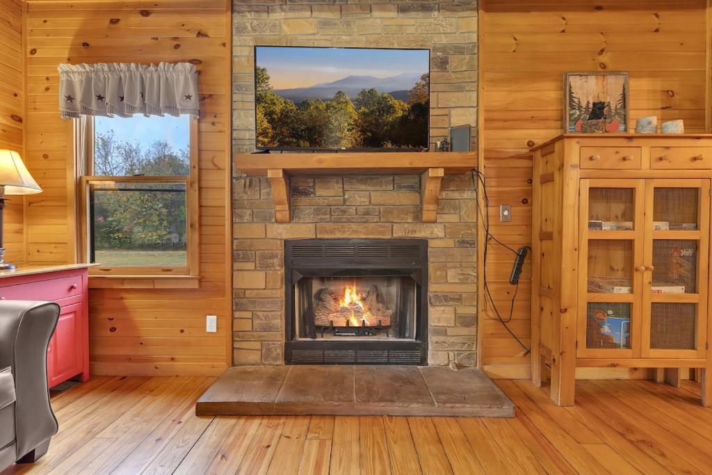 The stone fireplace in the living room, TV above the mantel · © Creekside Cabin