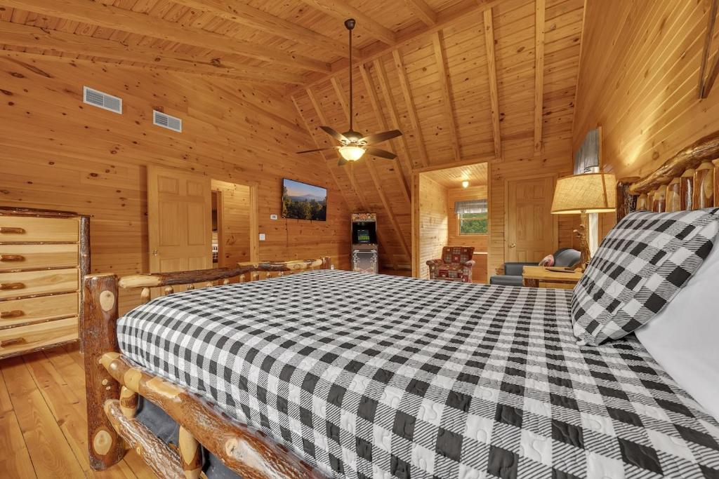 A log bed under the sloped ceiling, an arcade cabinet in the corner · © Creekside Cabin