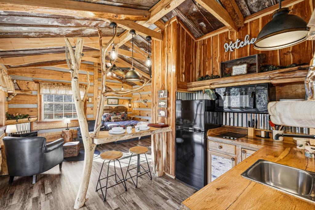 The open great room under a driftwood post, kitchen and bed in one space · © Creekside Treehouse