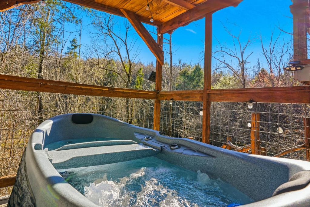 The private hot tub on the screened deck, bare winter woods beyond · © Creekside Treehouse