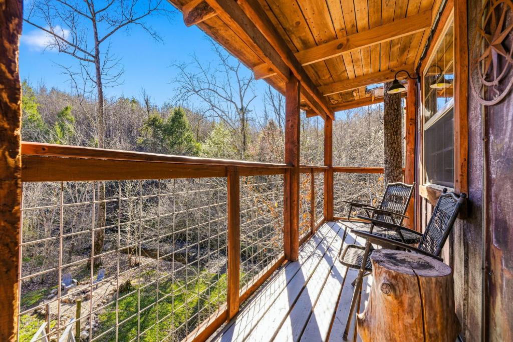 The elevated deck and its rail seating, perched over the creek bank · © Creekside Treehouse