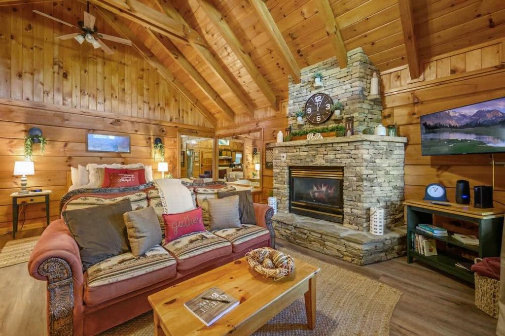 The sofa facing the stone fireplace under the pine ceiling · © Do Not Disturb