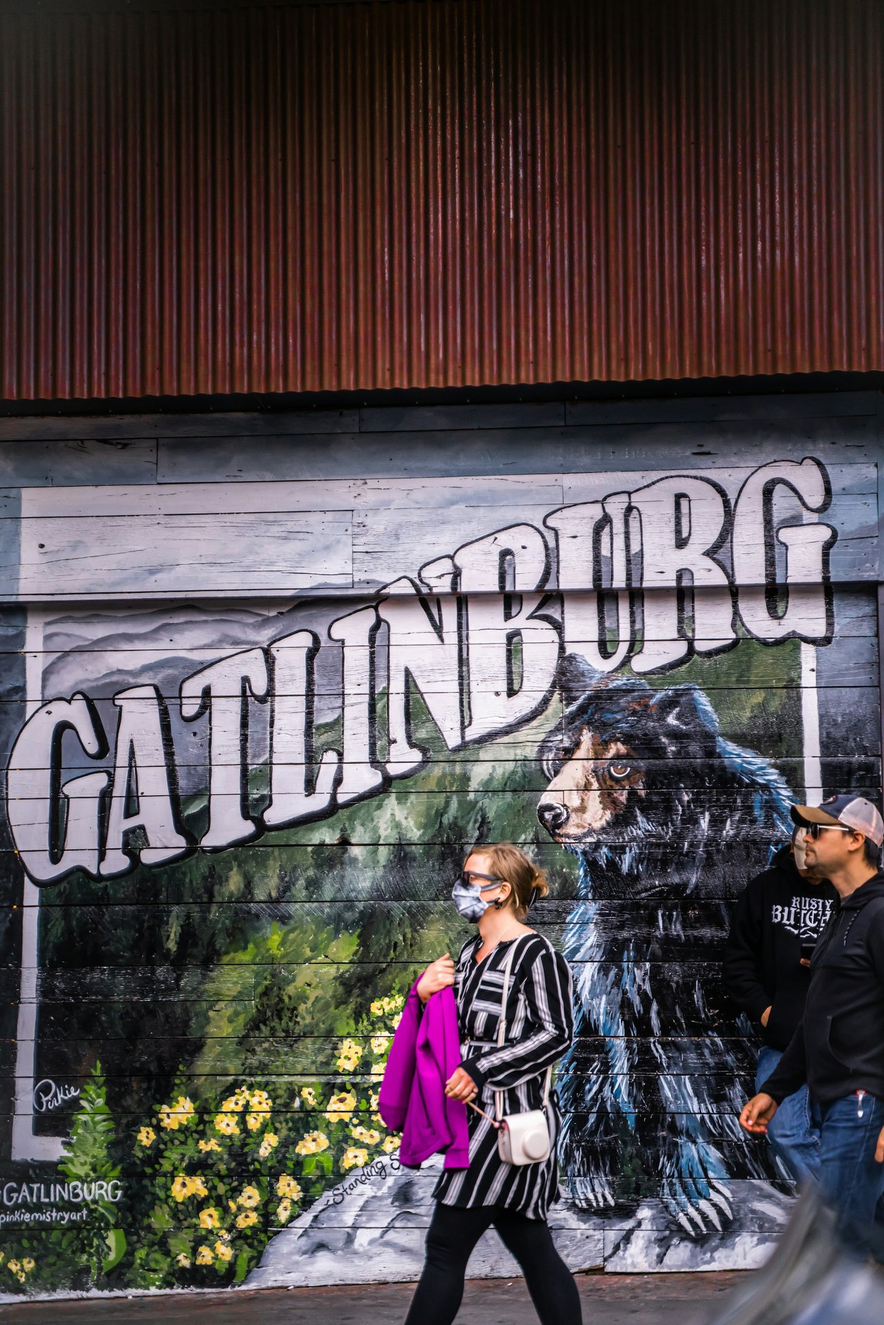 A painted Gatlinburg mural with a black bear, passers-by in front
