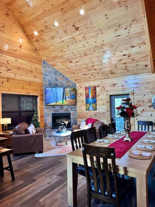 The open living and dining room under a vaulted ceiling, with a stone fireplace · © Enchanted Peak Lodge