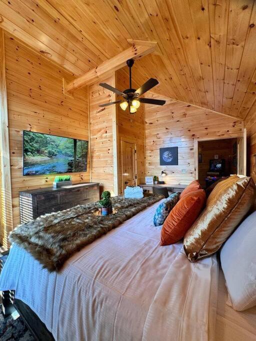 A king bedroom in knotty pine, dressed with a fur throw and a wall-mounted TV · © Enchanted Peak Lodge