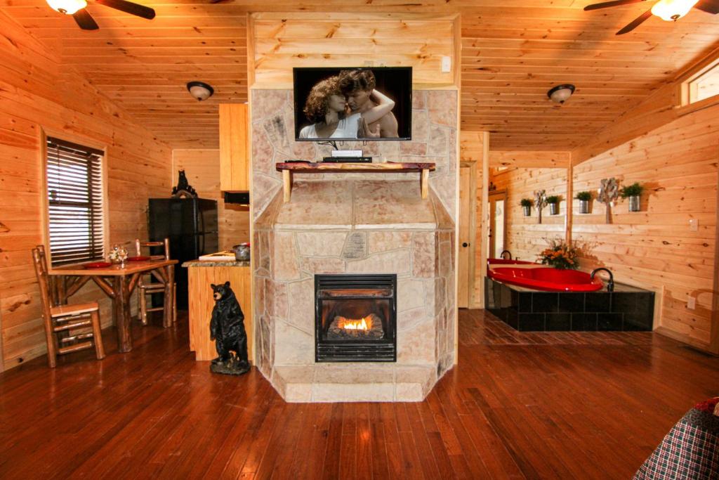 The open living room with a stone fireplace, kitchen and heart-shaped jetted tub · © Endless Mountain Dreams