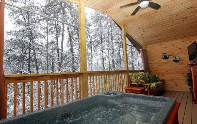 The private hot tub on the covered deck above the snow-dusted trees · © Endless Mountain Dreams