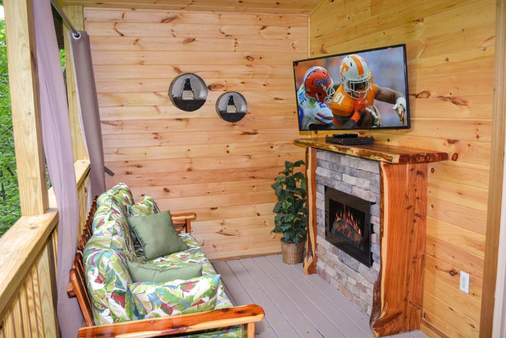 The screened porch with a futon and a second fireplace under the outdoor TV · © Endless Mountain Dreams