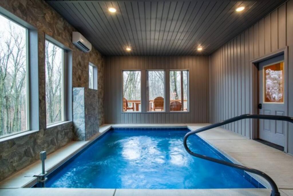 The private indoor pool under a plank ceiling, forest through the windows · © Escape to Nature's Embrace
