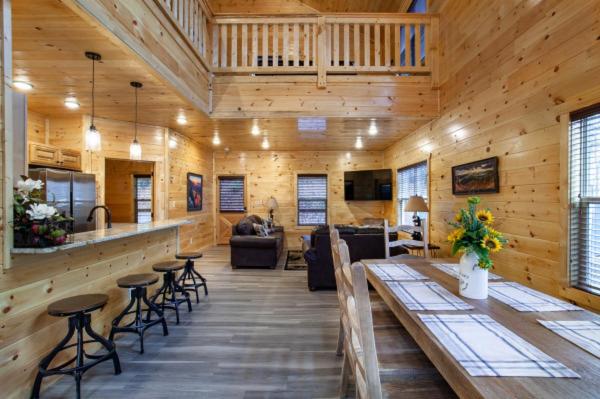 The open living and kitchen with a loft railing above · © Escape to Nature's Embrace