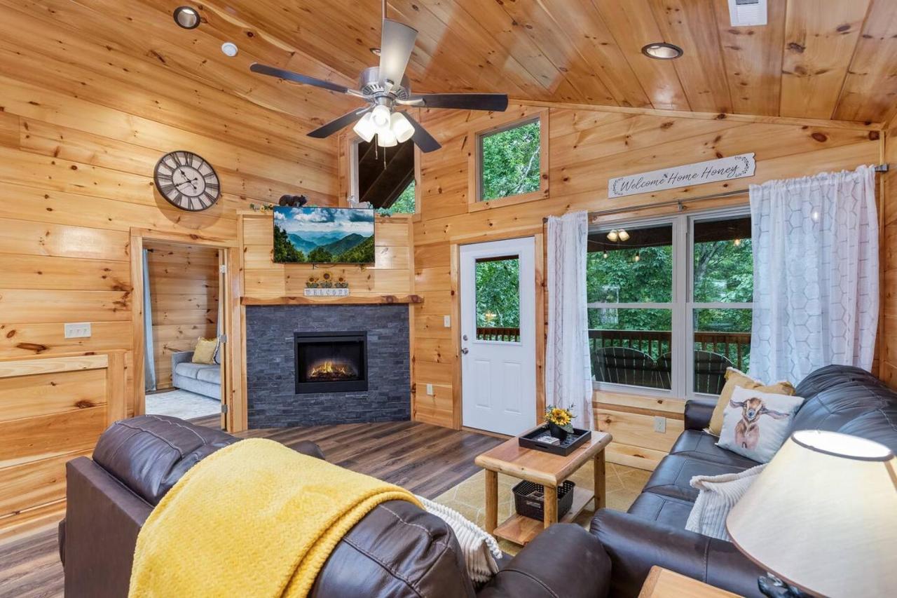 The living room with a stacked-stone fireplace and a deck door to the trees · © Goats & Honey Family Cabin