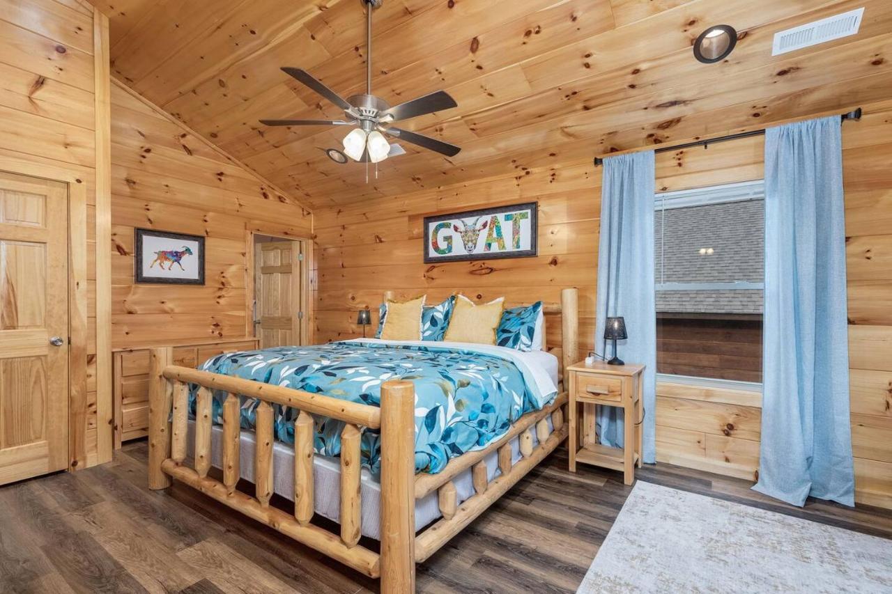 A king bedroom under a vaulted pine ceiling, with the cabin's goat motif · © Goats & Honey Family Cabin