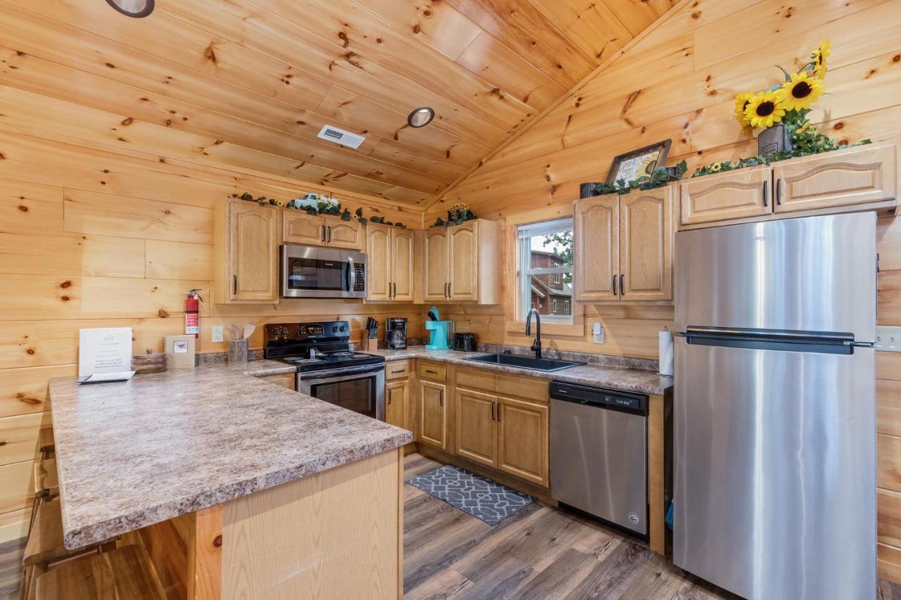 The full kitchen in knotty pine, with stainless appliances and a breakfast bar · © Goats & Honey Family Cabin