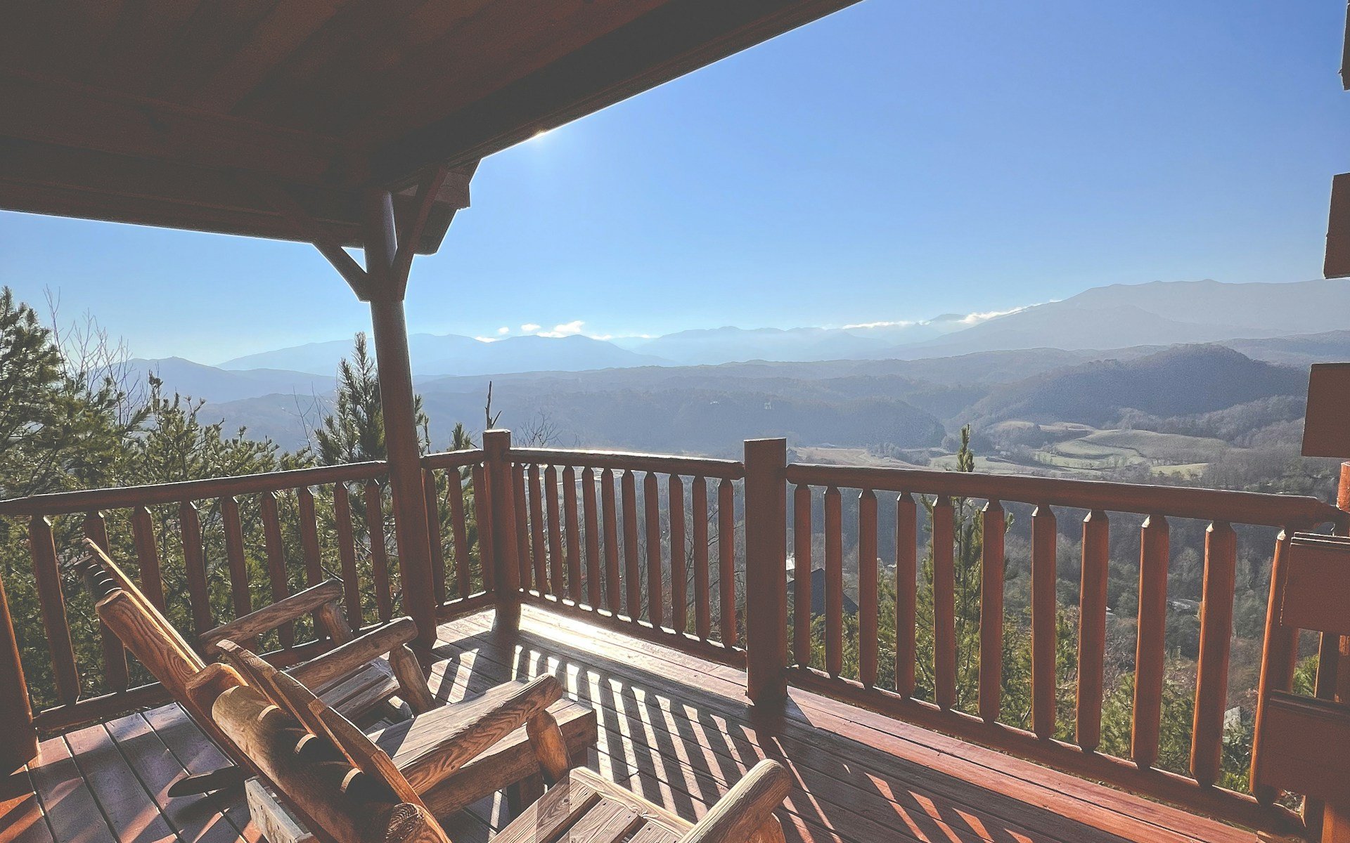 A covered cabin deck and a log chair facing the Smokies, Gatlinburg