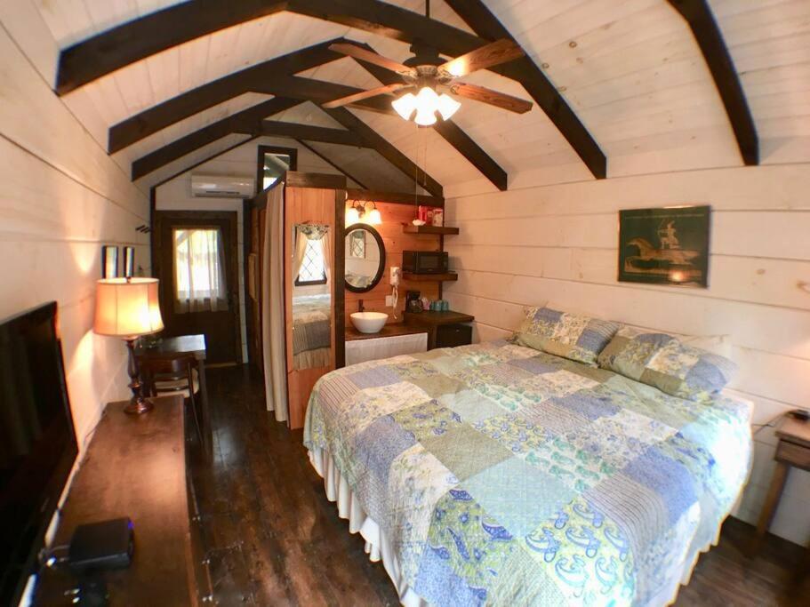 The king bed under a beamed, vaulted ceiling · © The Helena Tiny Home