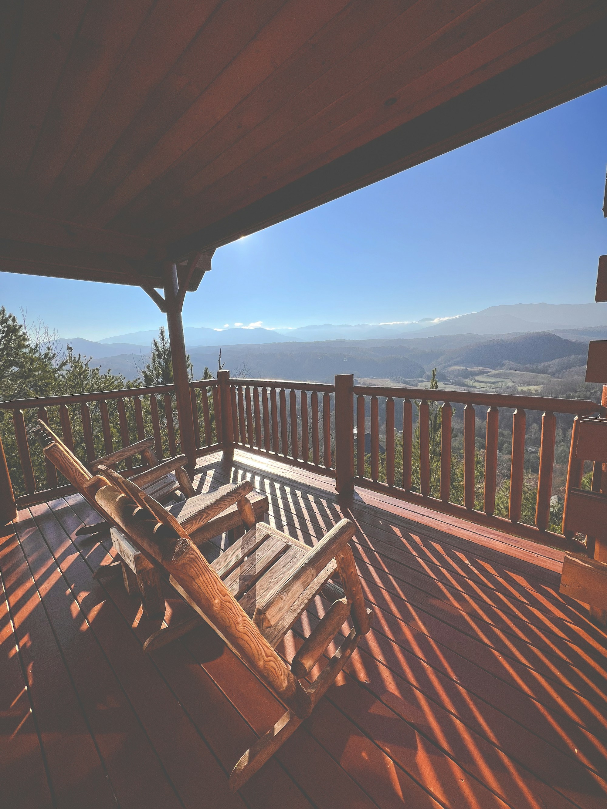 Two wooden rocking chairs on a log cabin porch overlooking the Great Smoky Mountains