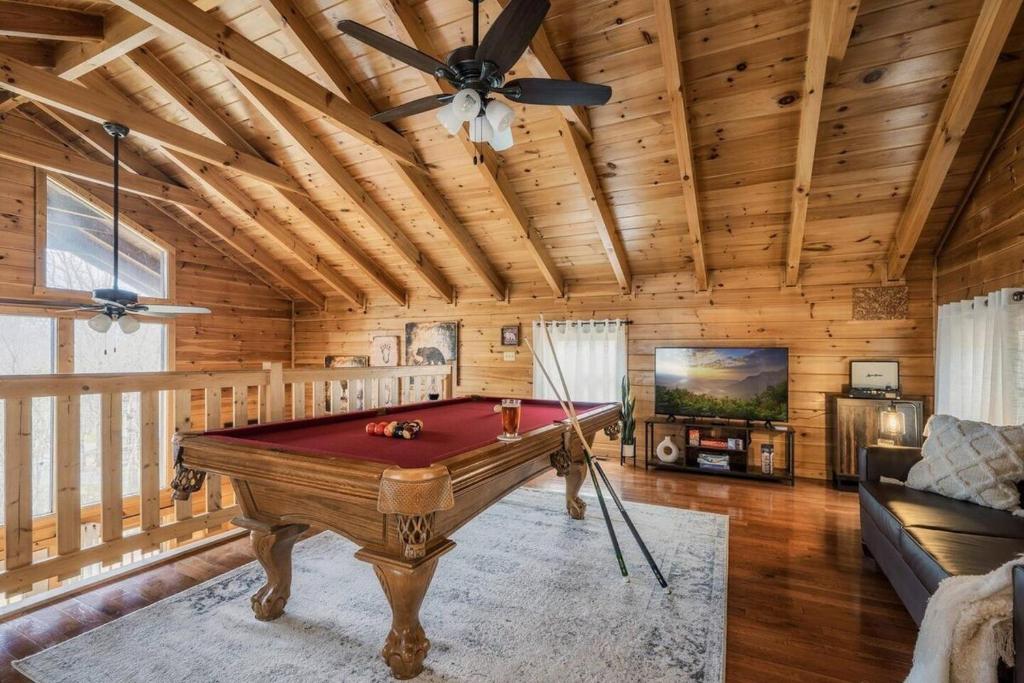 The game loft with a full pool table under pine beams · © Honeymoon Cabin