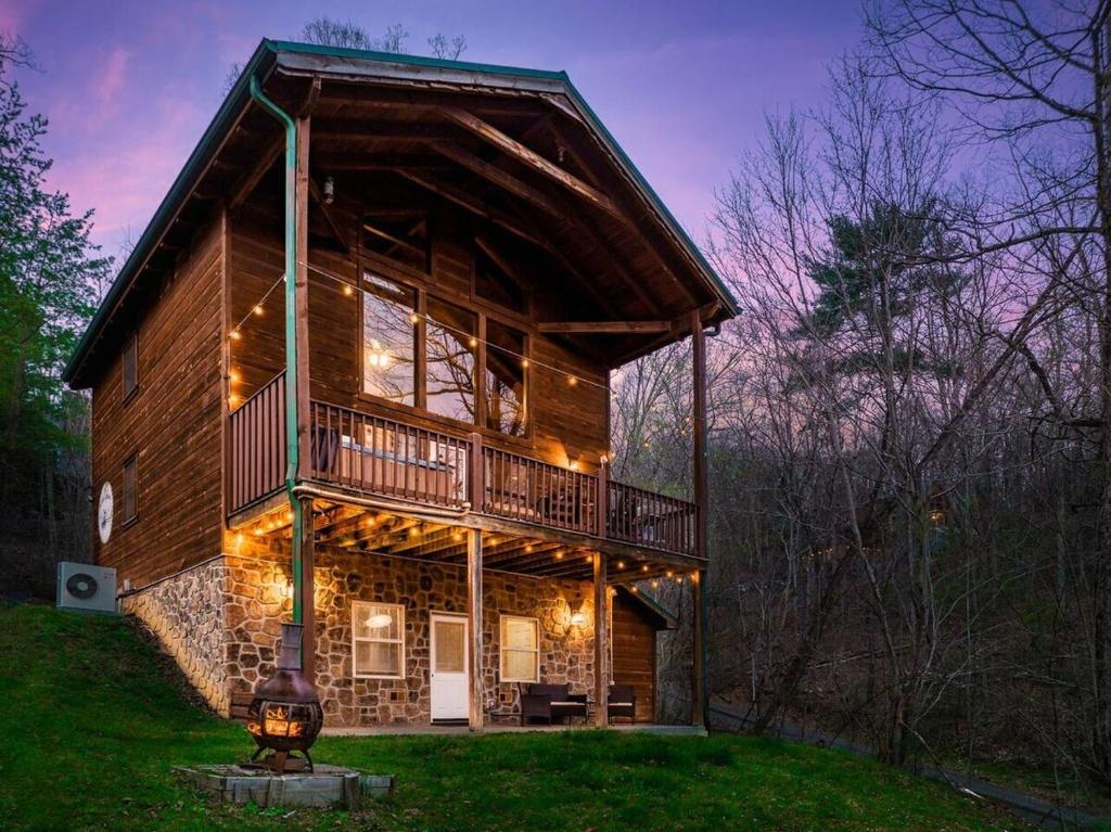 The two-story log cabin lit up at dusk · © Honeymoon Cabin