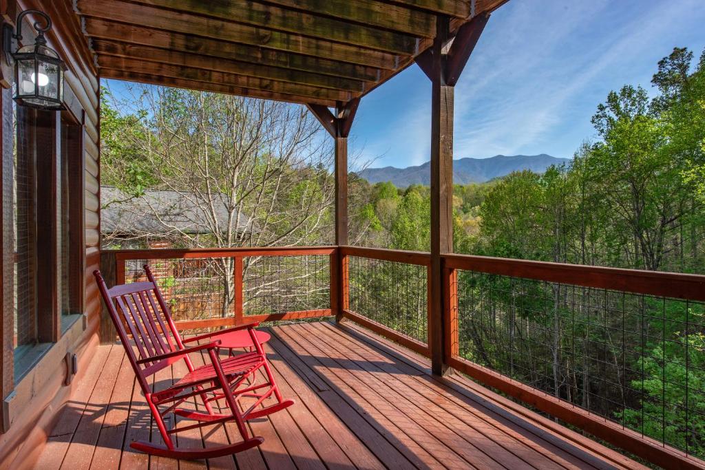 A red rocker on the covered deck, mountains past the trees · © I Love View Too