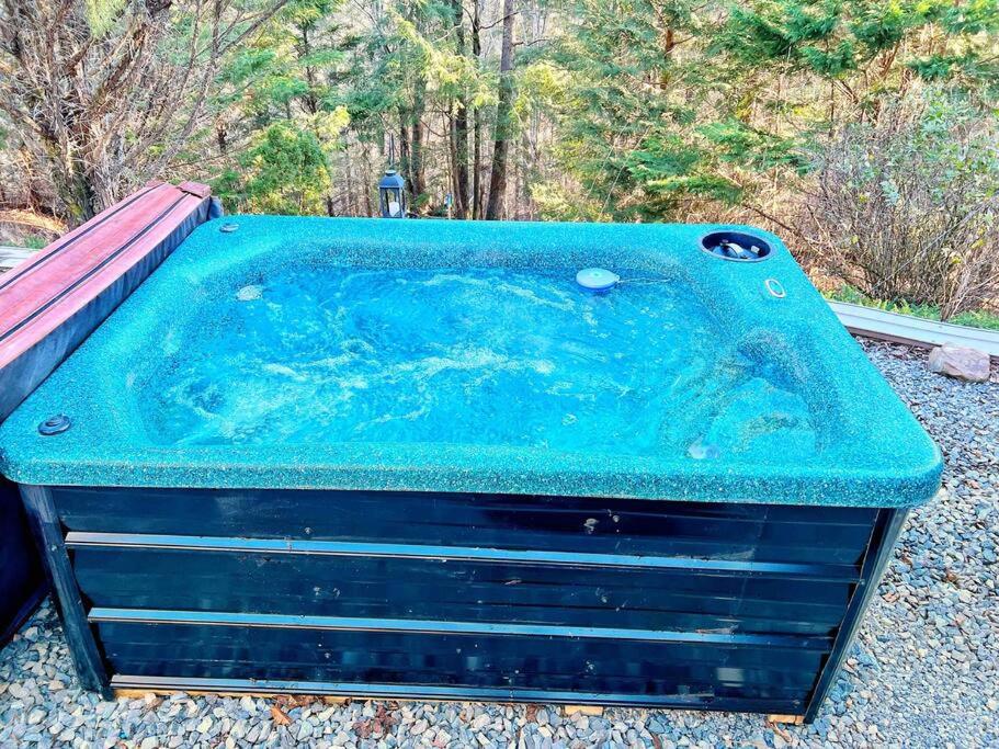 The private hot tub on its gravel pad, facing the trees · © Jones Cove Tiny House
