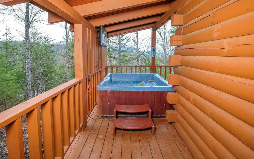 The covered hot tub on the deck, facing wooded ridges · © Knotty Escape