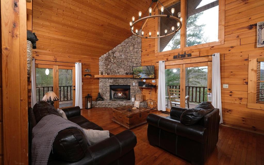 The great room's stone fireplace and French doors to the deck · © Knotty Escape
