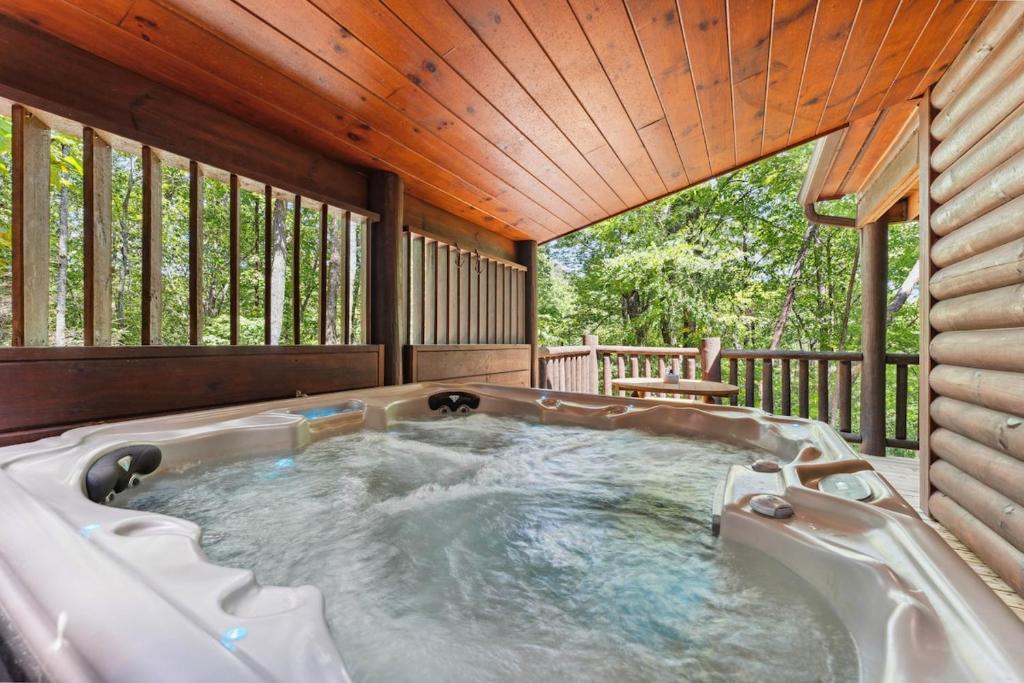 The private hot tub on the covered deck, open to the surrounding forest · © Little Pine Lodge